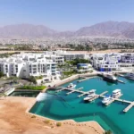 Aqaba Red Sea coastline with marinas, clear turquoise water, and surrounding desert mountains.
