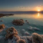 Dead Sea sunrise with salt formations and calm mineral-rich waters in Jordan