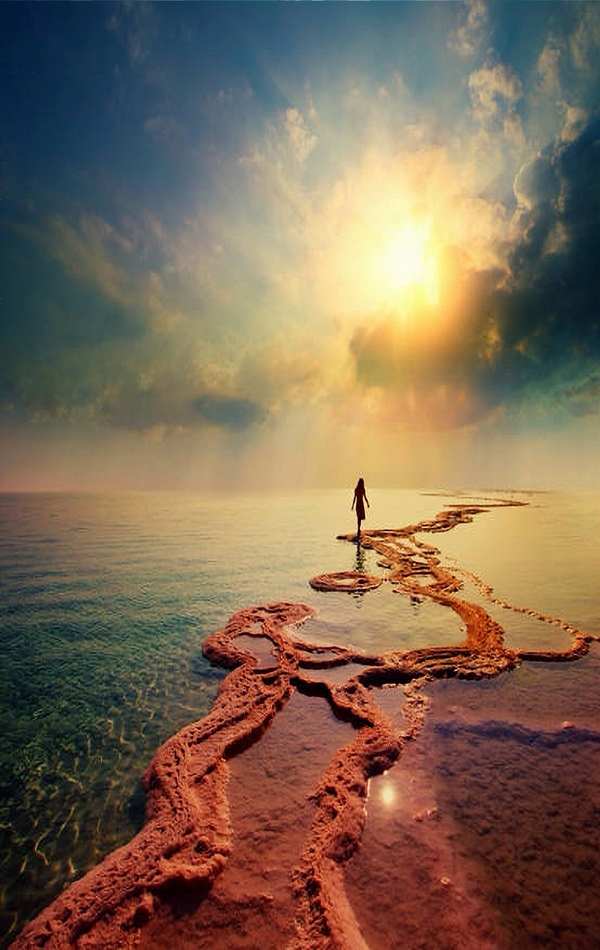 Woman walking on Dead Sea salt shore towards the sunB