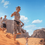Private group travellers walking on a red sand dune in Wadi Rum, Jordan