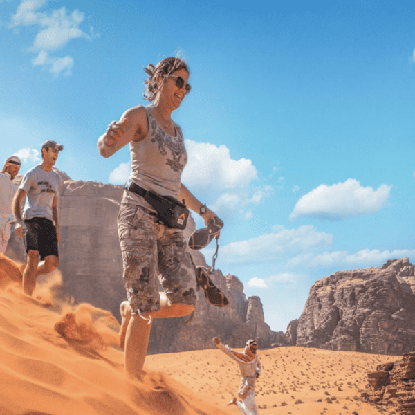 Private group travellers walking on a red sand dune in Wadi Rum, Jordan