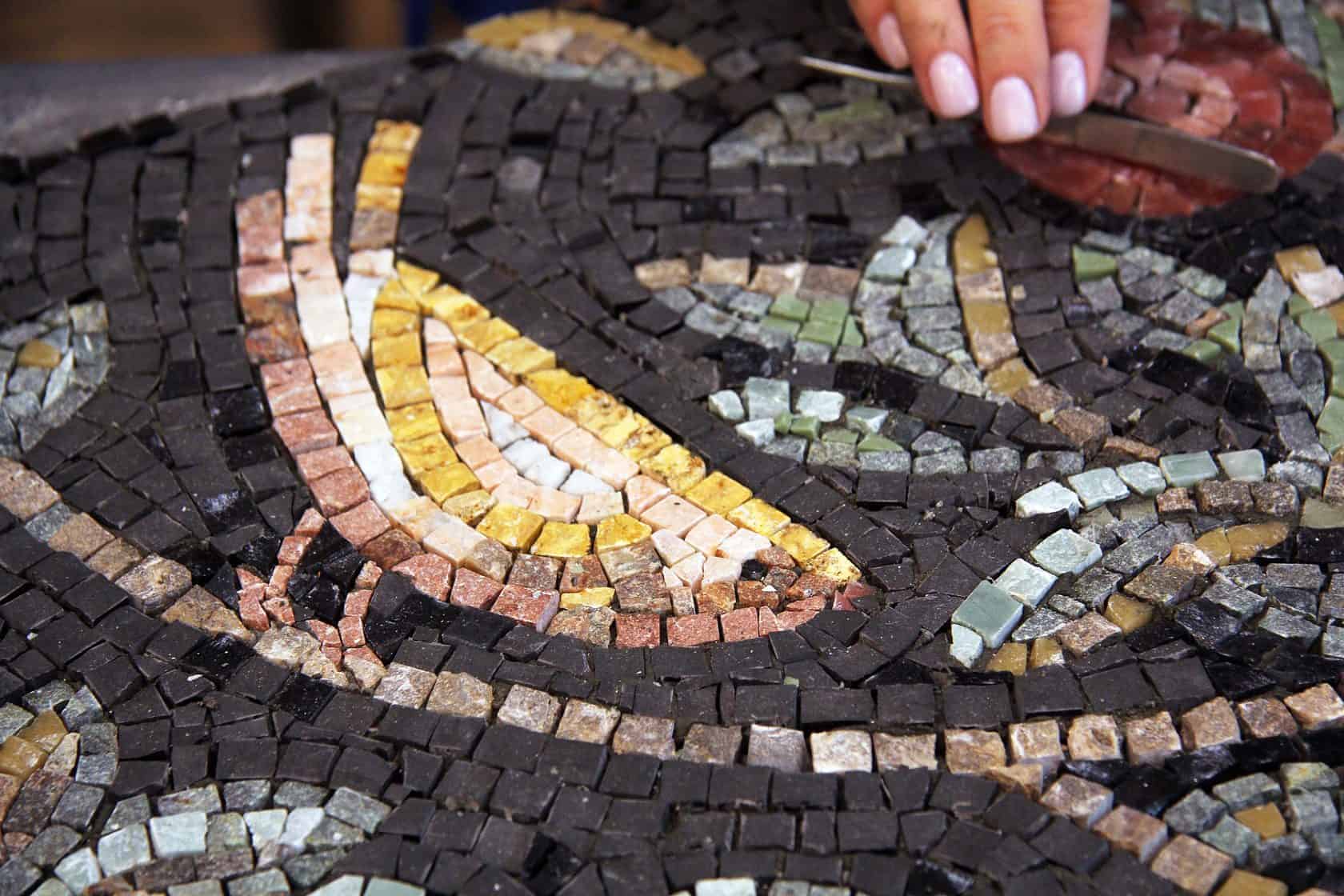Artigiano che compone un mosaico colorato con tessere di pietra a Madaba