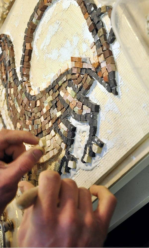 Artigiani che compongono un motivo a mosaico con tessere di pietra a Madaba